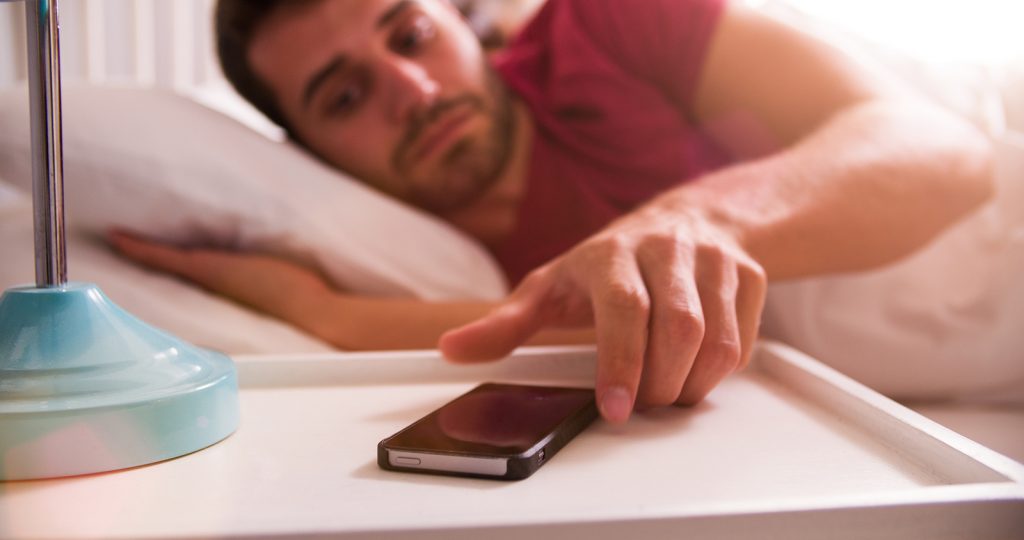 Man In Bed Woken By Alarm On Mobile Phone