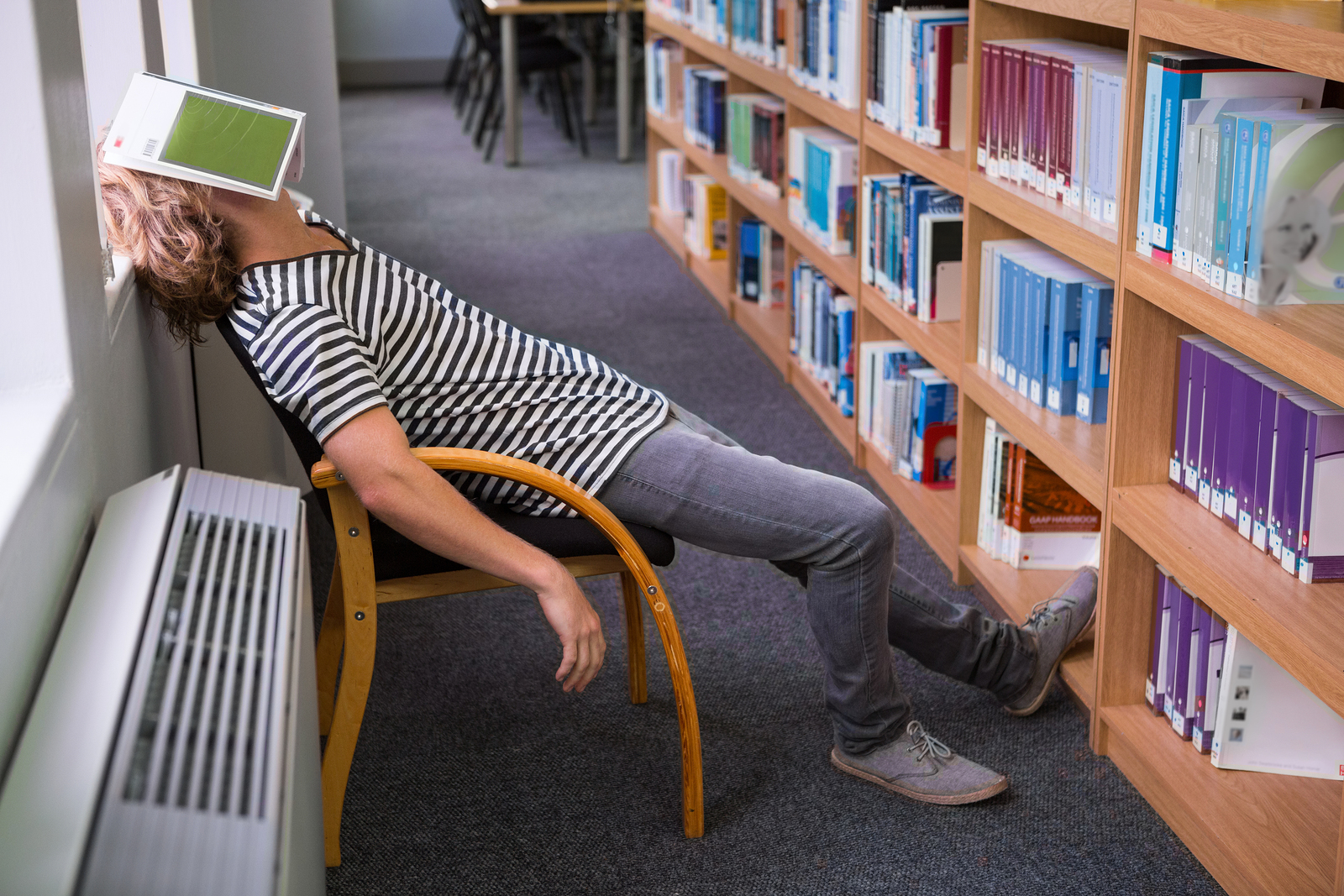 Student asleep in the library with book on his face at the unive