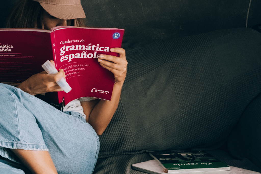 woman on couch reading a language textbook