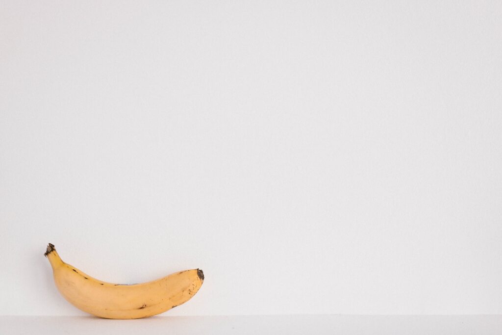 A banana against a white wall.