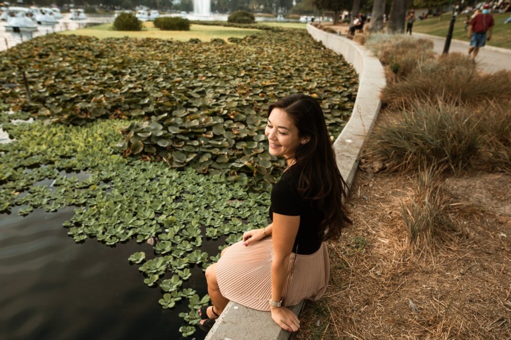 Happy woman sits next to pond