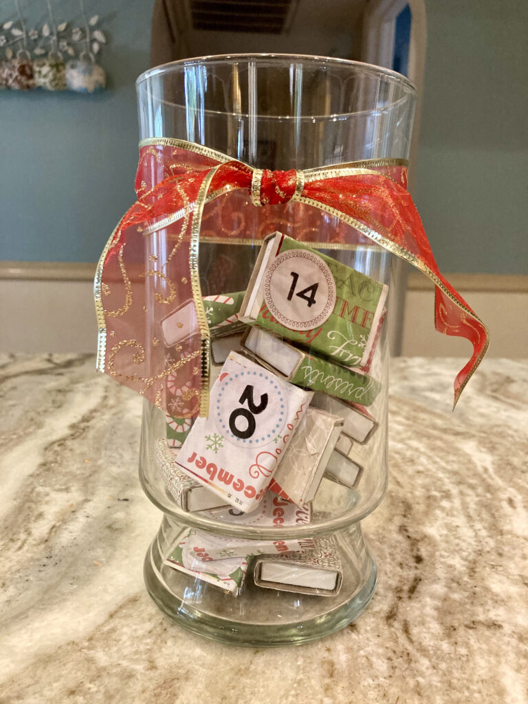 A clear vase with a red bow, filled with matchboxes. 
