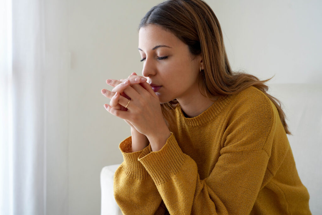 A young woman prays with her eyes closed.