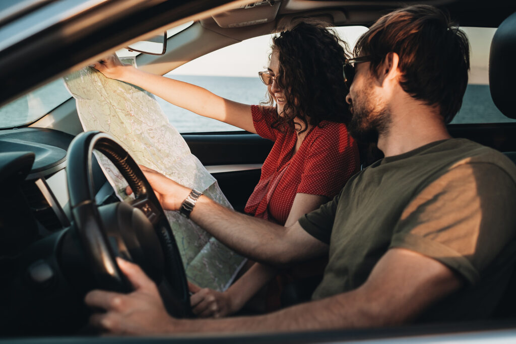 Two people sit in car looking at a map