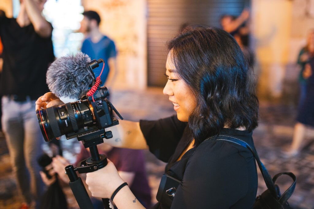 Young asian woman holding a camera with a microphone