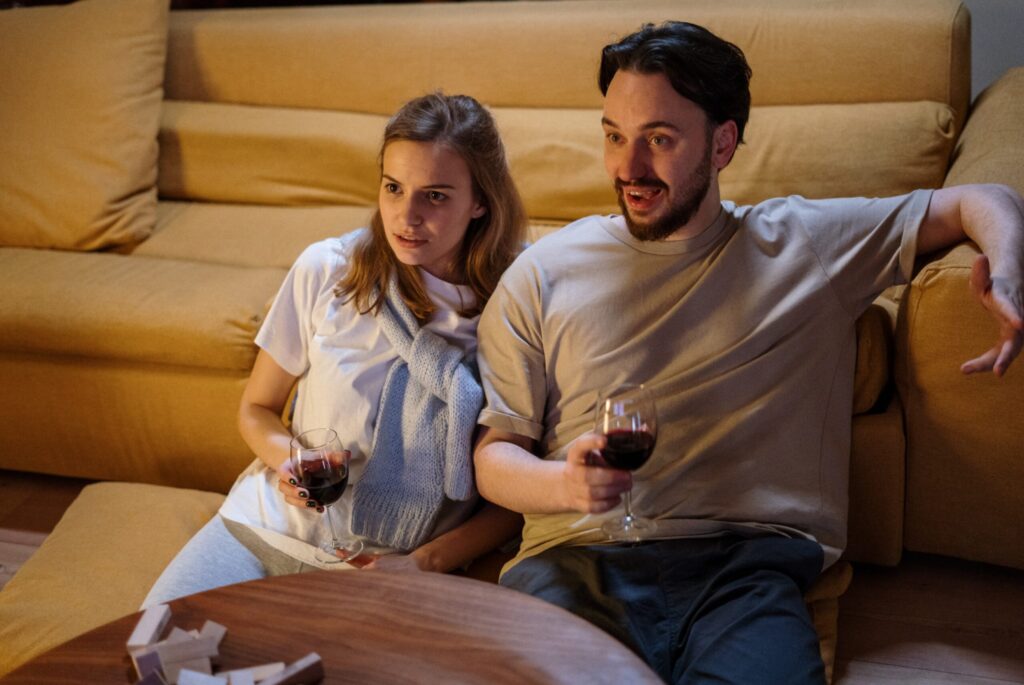 Man and woman sitting on the floor with wine watching TV.