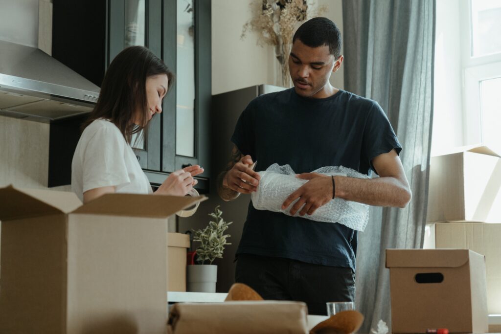 A woman and a man putting items into boxes in preparation for moving.