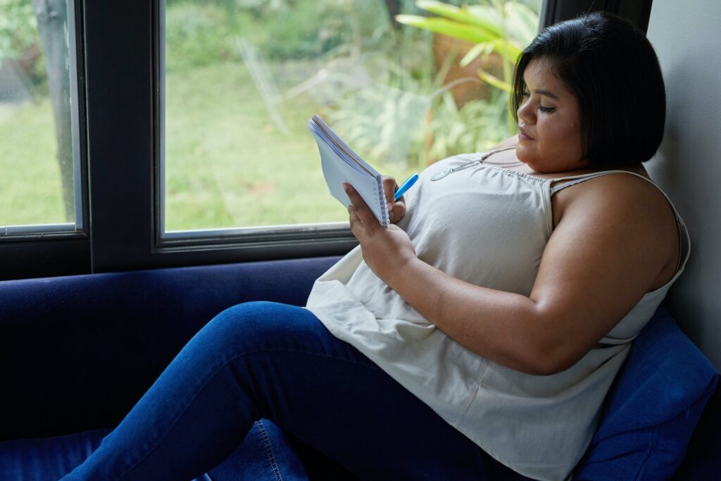Woman sitting on window seat journaling