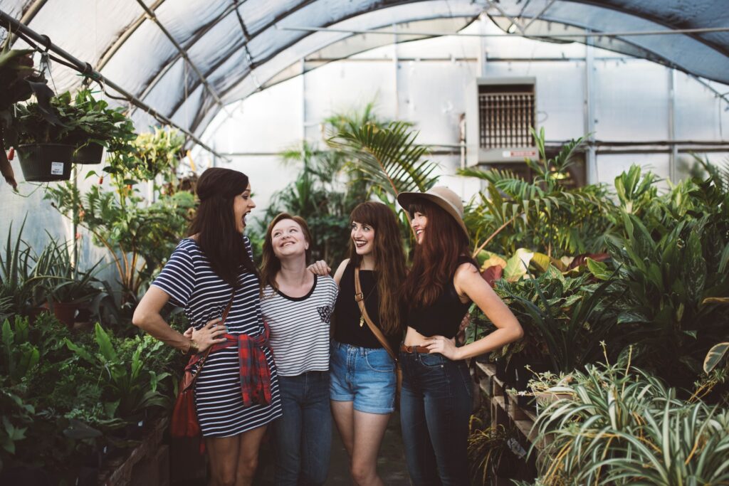 Group of four women standing together smiling in a garden