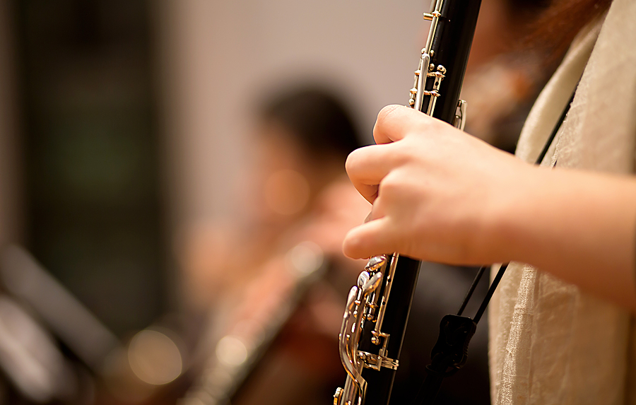 Image of person's hands holding an oboe and playing the instrument.